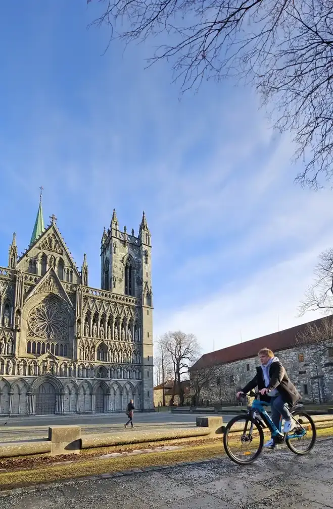 Person på elsykkel med Nidarosdomen i bakgrunn